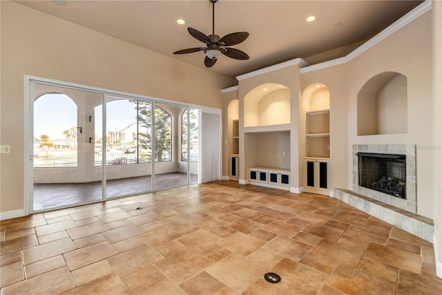 unfurnished living room featuring a tiled fireplace, built in features, and ceiling fan