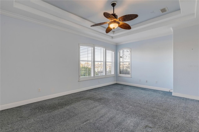 empty room with ornamental molding, carpet floors, ceiling fan, and a tray ceiling