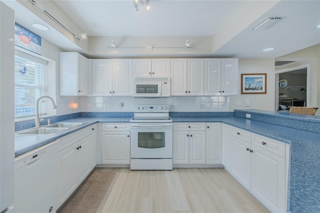 kitchen with white cabinetry, sink, white appliances, and light hardwood / wood-style flooring