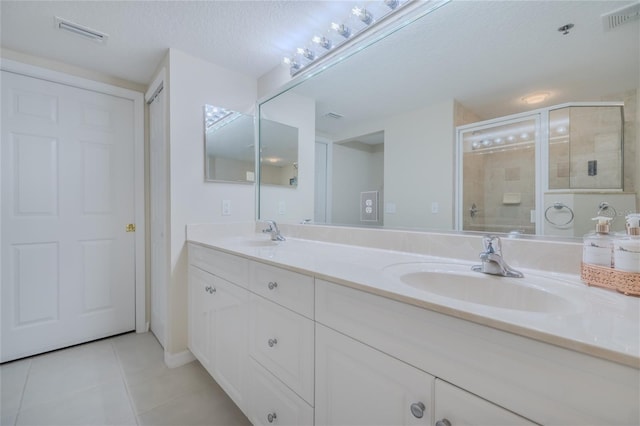 bathroom with walk in shower, tile patterned floors, vanity, and a textured ceiling