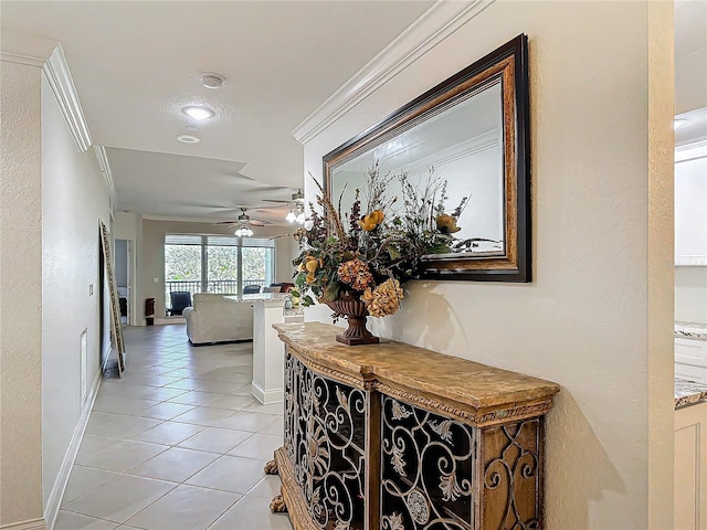 hall featuring baseboards, light tile patterned flooring, and crown molding