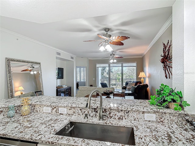 kitchen with light stone counters, a sink, visible vents, open floor plan, and ornamental molding