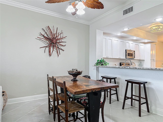 dining room featuring visible vents, crown molding, baseboards, and light tile patterned flooring