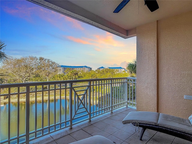 balcony at dusk featuring ceiling fan and a water view