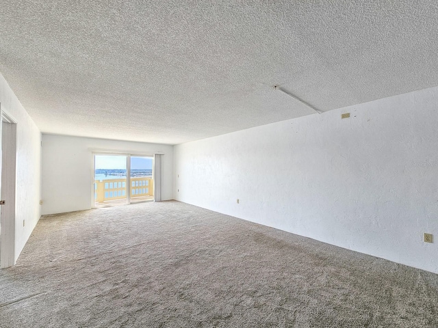 spare room with a water view, carpet flooring, and a textured ceiling