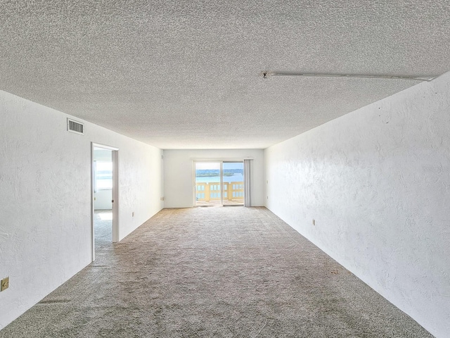 carpeted empty room featuring a textured ceiling