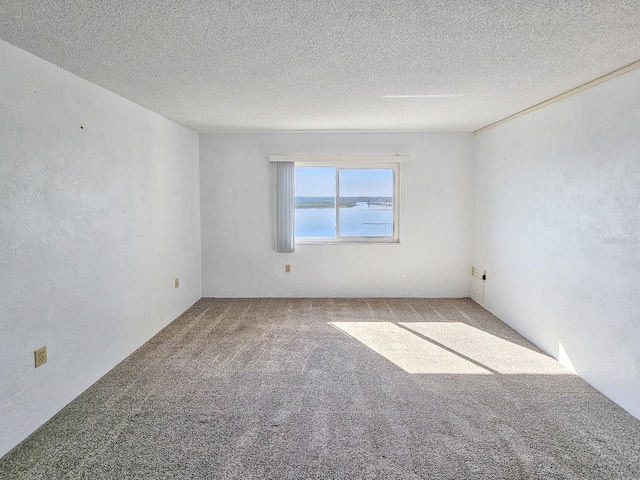 spare room featuring a water view, carpet, and a textured ceiling