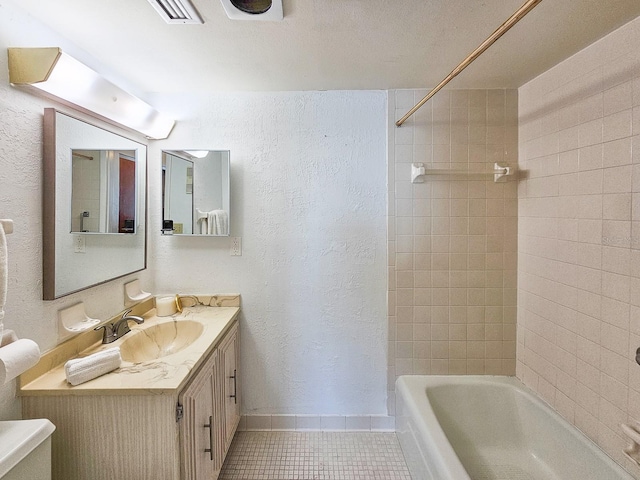 full bathroom with tiled shower / bath, tile patterned floors, toilet, and vanity