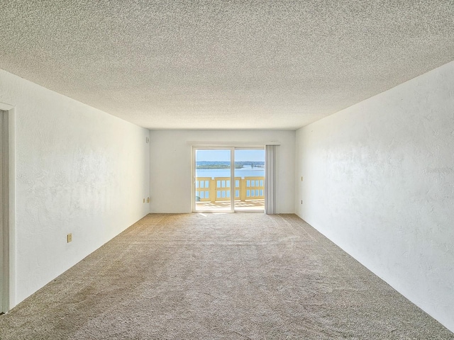 carpeted spare room with a water view and a textured ceiling