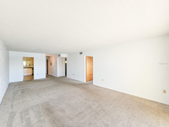 unfurnished living room with carpet floors and a textured ceiling