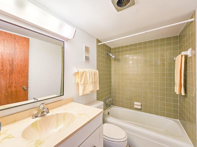 full bathroom featuring vanity, tiled shower / bath combo, and toilet