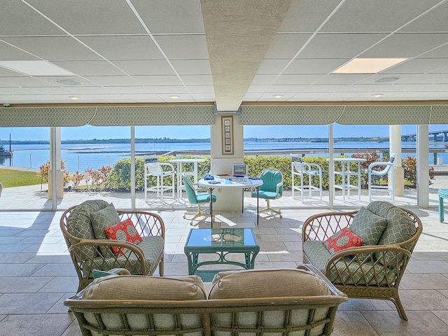 sunroom / solarium featuring a paneled ceiling and a water view