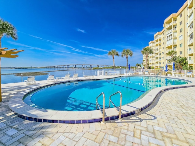 view of pool with a water view and a patio area