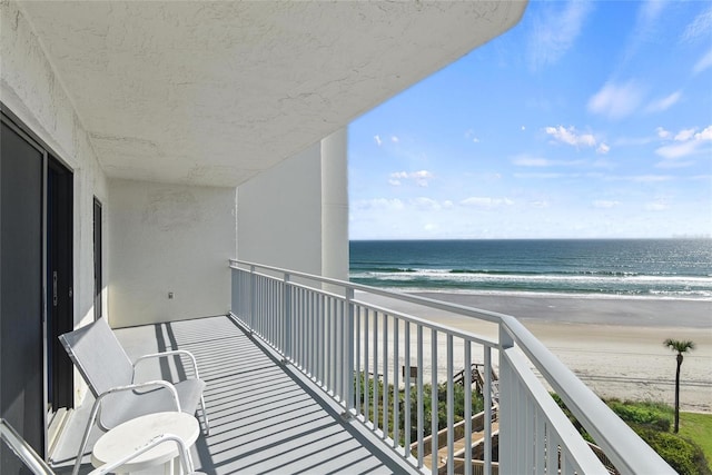 balcony with a water view and a view of the beach