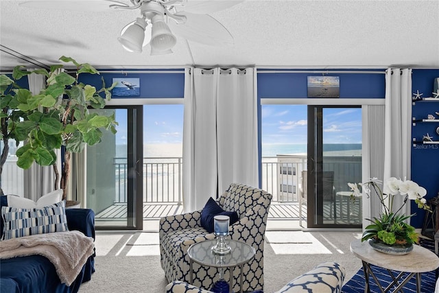 living room featuring a water view, carpet floors, a textured ceiling, and a wealth of natural light