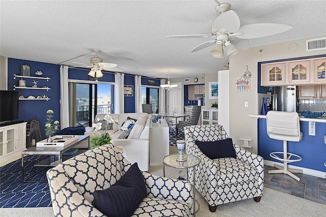 living room with ceiling fan with notable chandelier and a textured ceiling