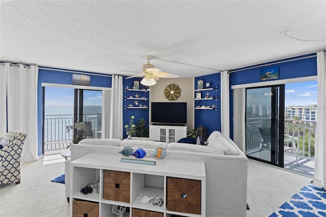 carpeted living room with ceiling fan, plenty of natural light, and a textured ceiling