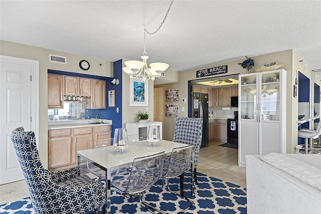 dining space with sink, light tile patterned floors, a chandelier, and a textured ceiling