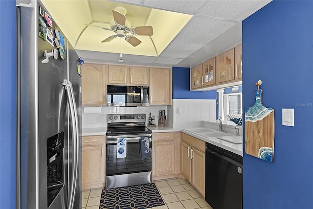 kitchen featuring appliances with stainless steel finishes, light brown cabinetry, sink, backsplash, and light tile patterned floors