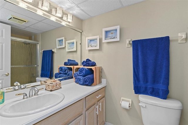 bathroom featuring a paneled ceiling, vanity, toilet, and an enclosed shower