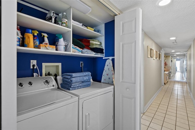 laundry area with washer and clothes dryer, a textured ceiling, and light tile patterned flooring