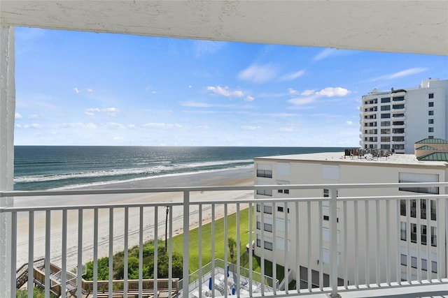 balcony with a water view and a view of the beach