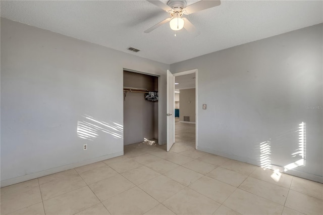 unfurnished bedroom featuring ceiling fan, light tile patterned flooring, a textured ceiling, and a closet