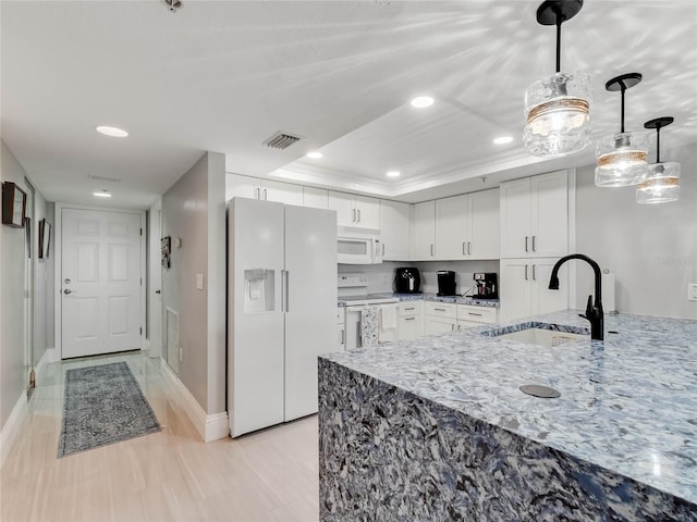 kitchen with sink, white cabinets, hanging light fixtures, a tray ceiling, and white appliances