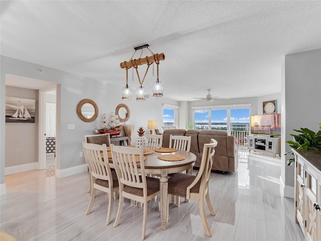 dining area featuring ceiling fan and a textured ceiling