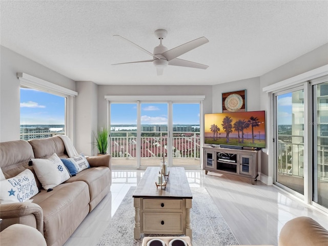 living room featuring ceiling fan, a healthy amount of sunlight, and a textured ceiling