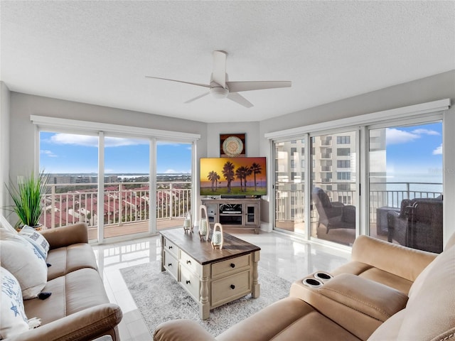 living room with ceiling fan, a wealth of natural light, a textured ceiling, and light tile patterned floors