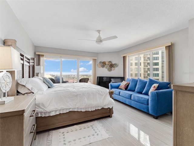 bedroom with ceiling fan, access to exterior, and a textured ceiling