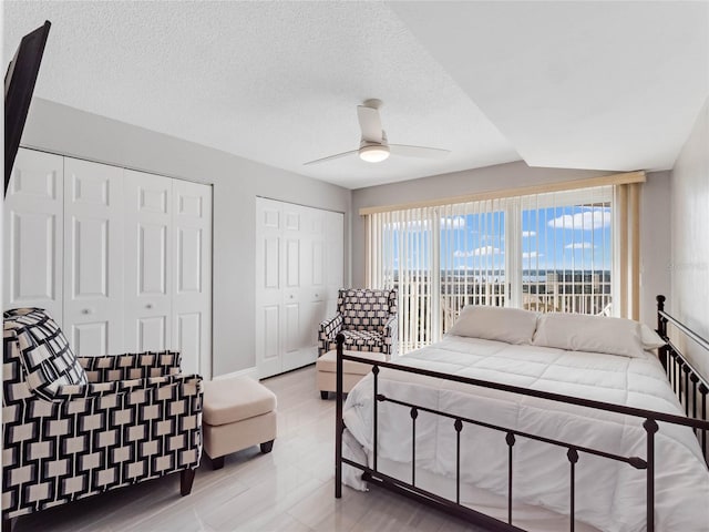 bedroom with multiple closets, ceiling fan, and a textured ceiling