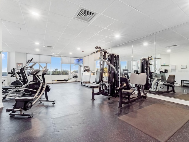 exercise room with a healthy amount of sunlight and a drop ceiling