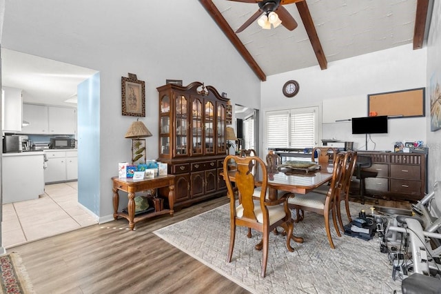 dining space featuring ceiling fan, high vaulted ceiling, beam ceiling, and light hardwood / wood-style flooring