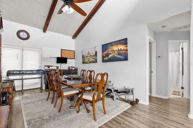 dining room with ceiling fan, lofted ceiling with beams, and light hardwood / wood-style flooring