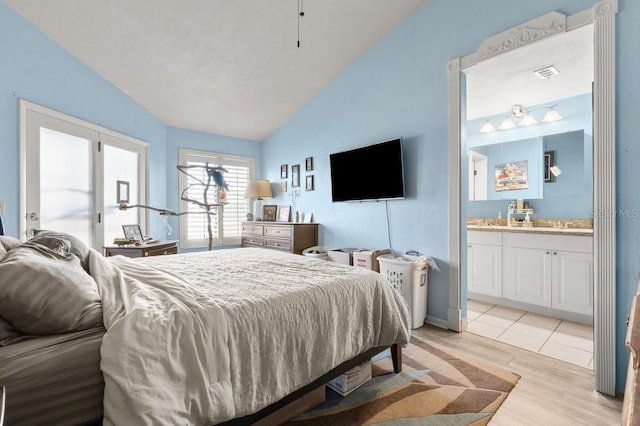 bedroom featuring vaulted ceiling, ensuite bathroom, and light wood-type flooring