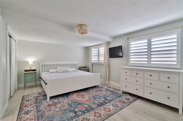 bedroom with a textured ceiling and light wood-type flooring