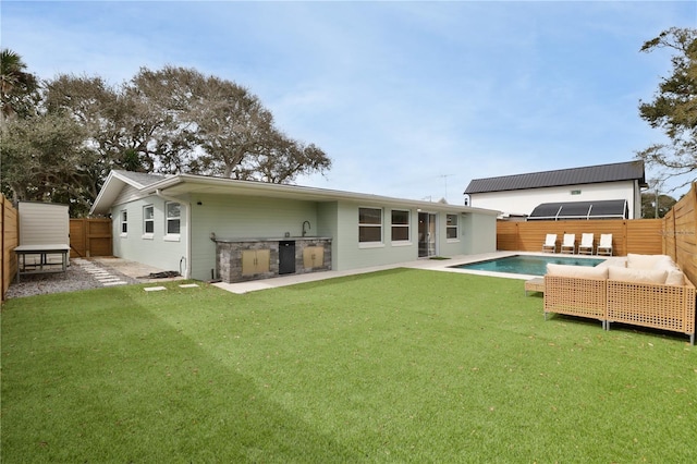 rear view of property featuring an outdoor kitchen, a yard, and a patio area