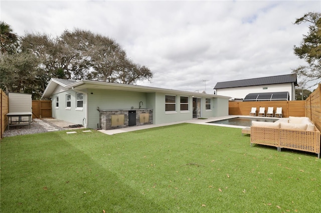 rear view of property with an outdoor hangout area, exterior kitchen, a patio area, and a lawn