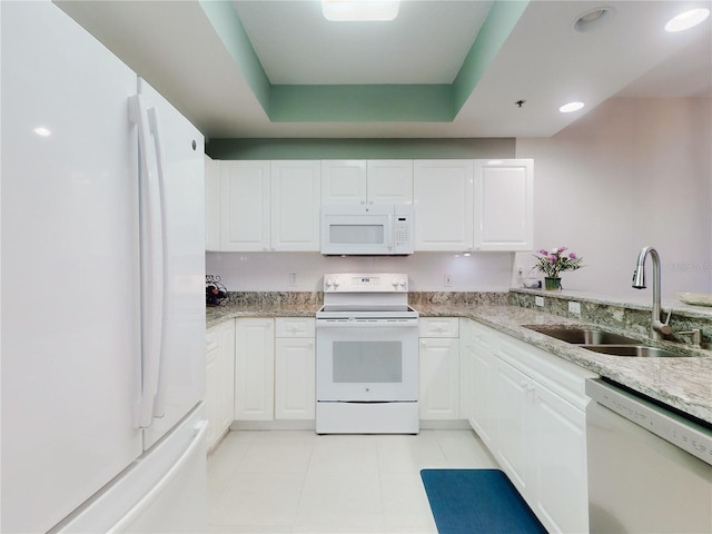 kitchen featuring white cabinetry, sink, a tray ceiling, light stone countertops, and white appliances