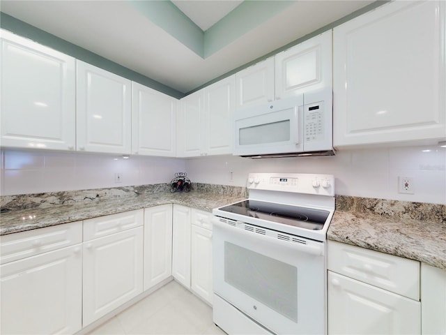 kitchen with light stone countertops, white cabinets, and white appliances