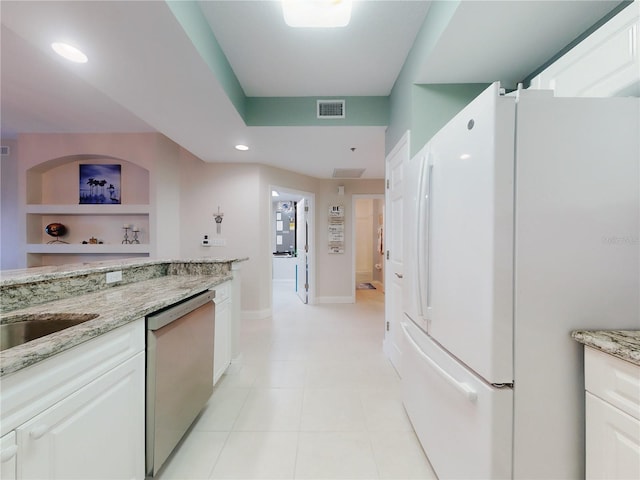 kitchen with white fridge, stainless steel dishwasher, white cabinets, and light stone counters