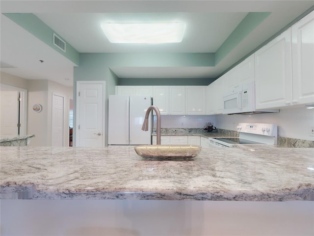 kitchen with white cabinetry, light stone counters, white appliances, and sink