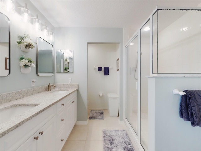 bathroom featuring tile patterned flooring, vanity, a shower with door, and toilet