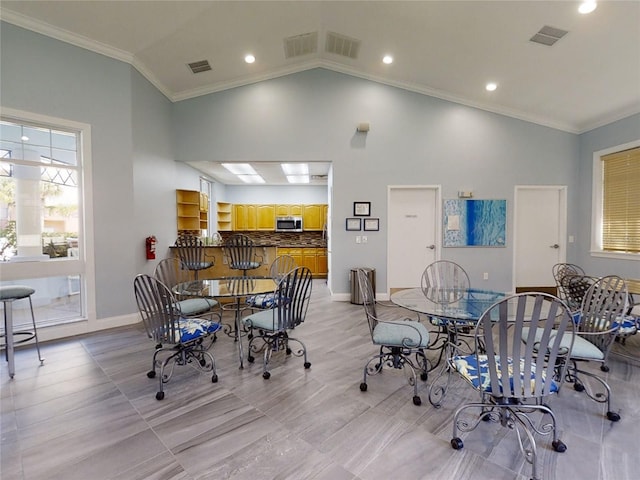 dining space featuring ornamental molding and high vaulted ceiling