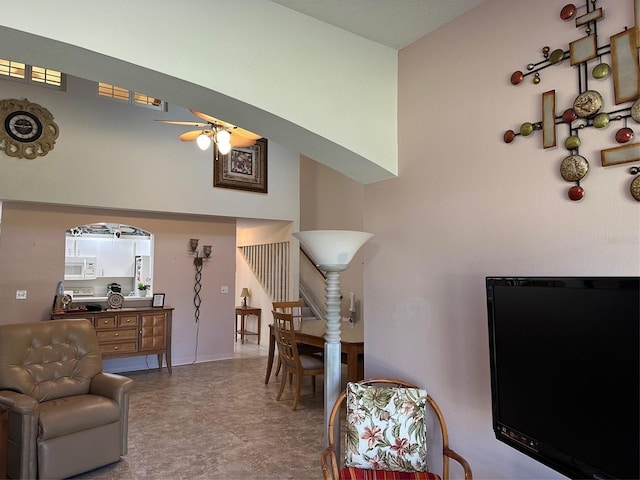 living area featuring stairway, ceiling fan, and a towering ceiling