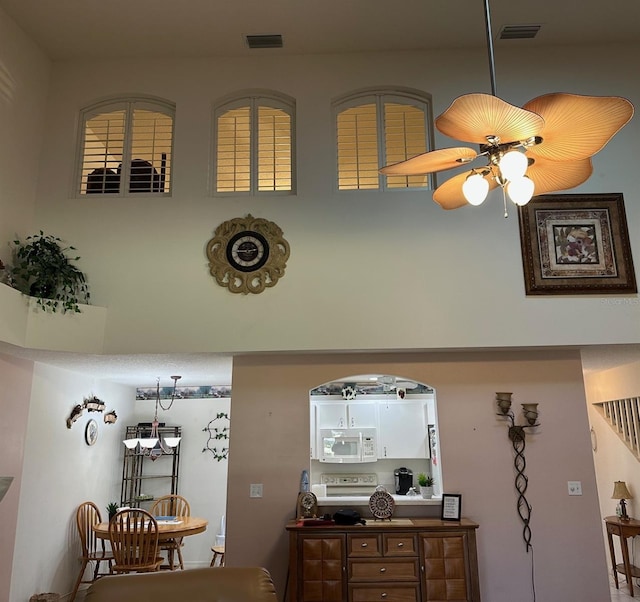 room details featuring range, white microwave, visible vents, and ceiling fan