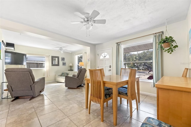 tiled dining space with a textured ceiling and ceiling fan