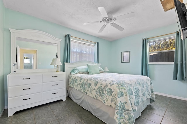 tiled bedroom with ceiling fan, multiple windows, and a textured ceiling